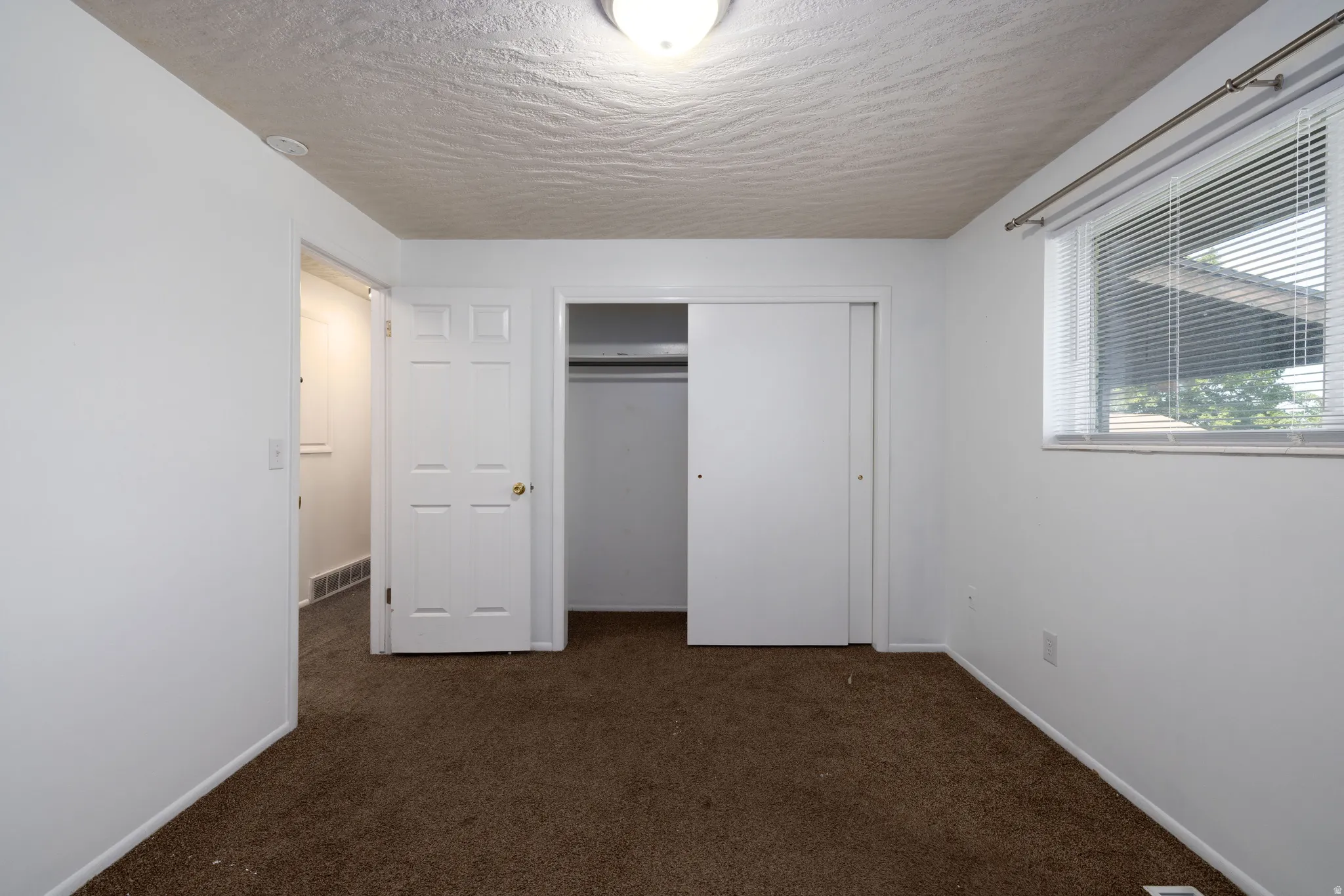 Wall-to-wall carpeting, window with blinds, and white interior doors