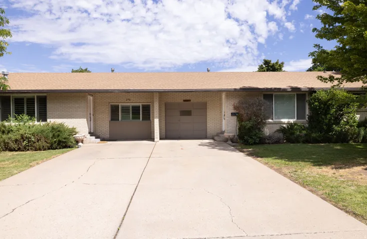 Light brick exterior with a brown shingle roof, integrated garage, and a concrete driveway