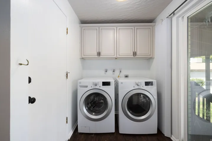 Laundry area featuring upper cabinetry, dark wood-finish flooring, and a sliding glass door