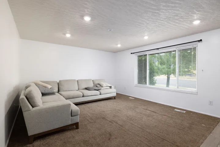 Recessed ceiling lighting, textured ceiling, expansive window with horizontal blinds, and wall-to-wall carpeting