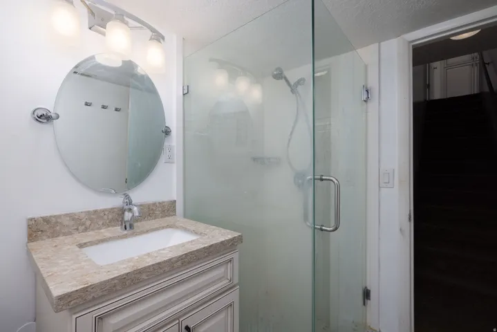 Vanity with integrated sink, stone-finish countertop, and white cabinetry