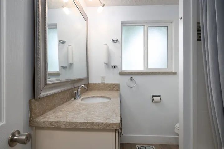 Vanity with a polished chrome faucet, under-mount sink, and stone countertop