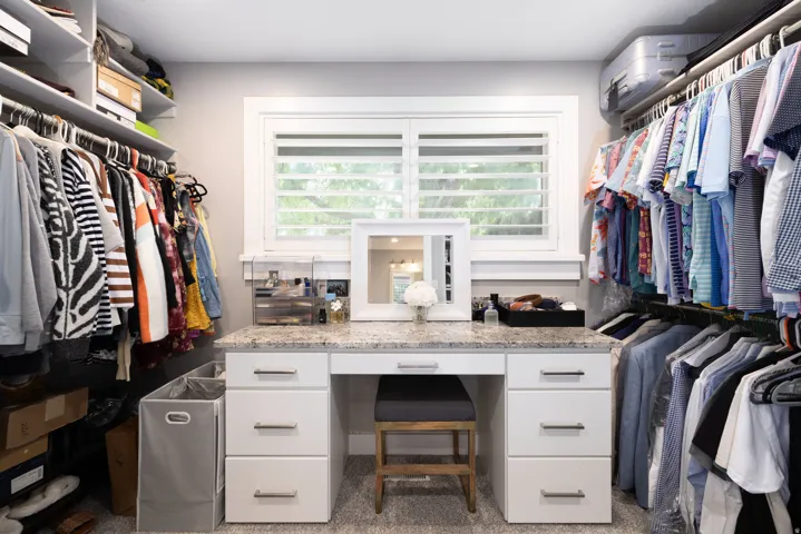 Built-in closet system with shelving, hanging rods, and a window with plantation shutters