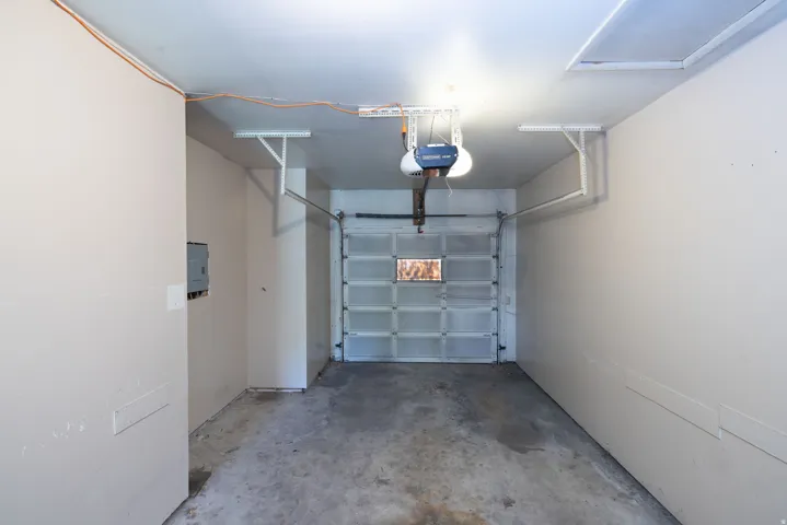Single-car garage with a sectional overhead door, automatic garage door opener, and painted walls