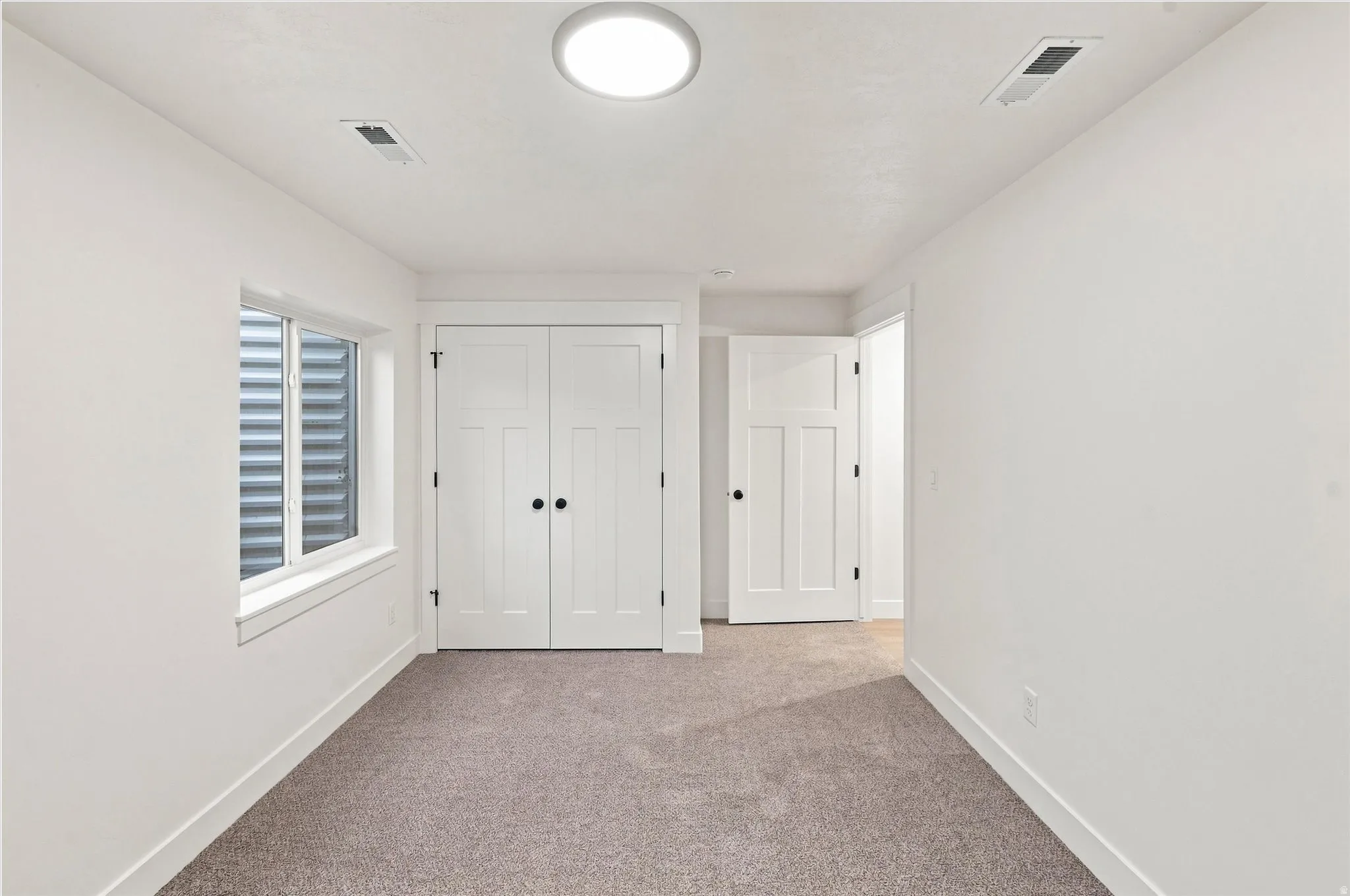 White walls, neutral carpet, and white trim create a bright interior