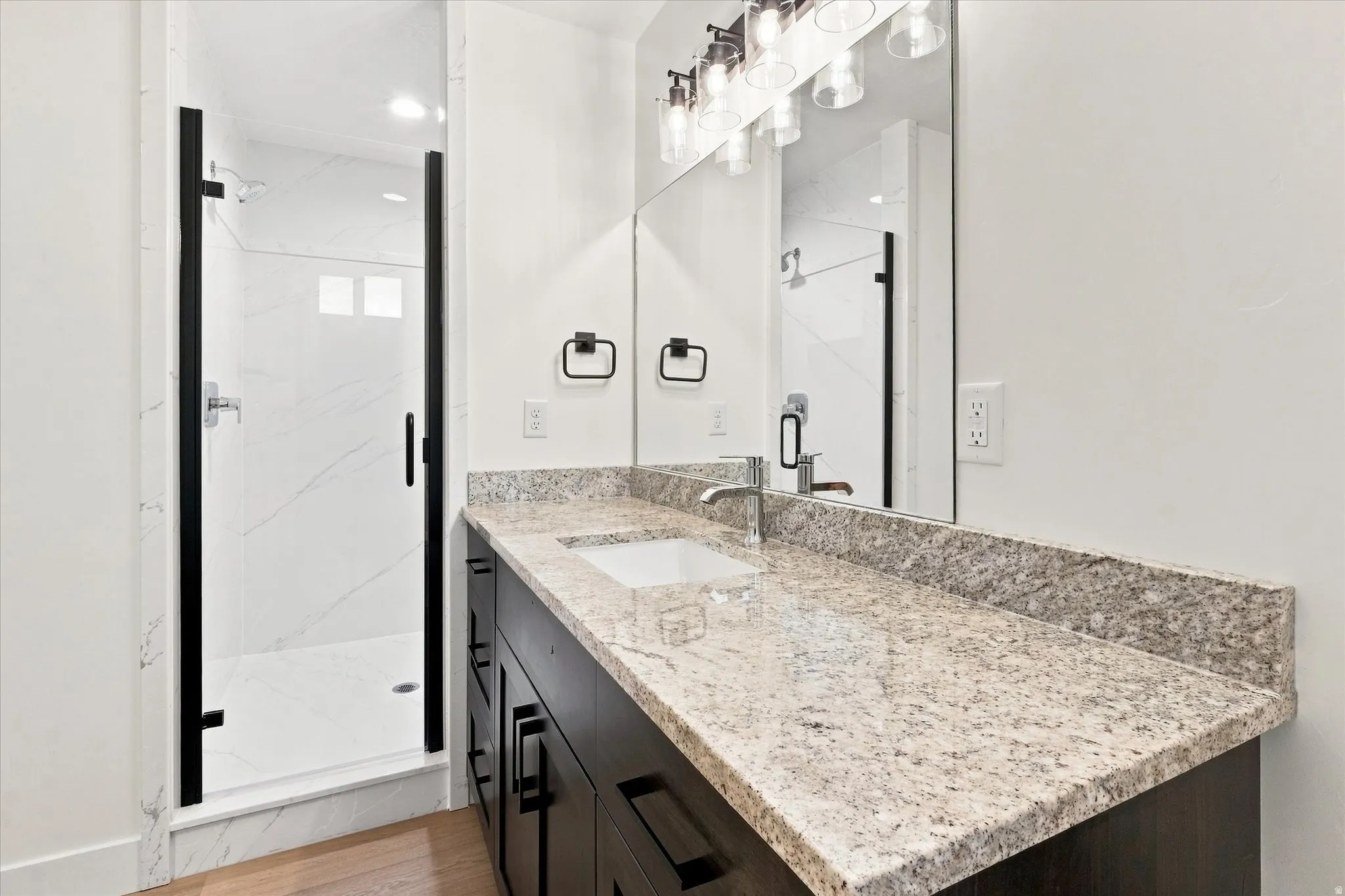Built-in dark wood vanity with a light-toned stone countertop, undermount sink, and chrome-finish faucet