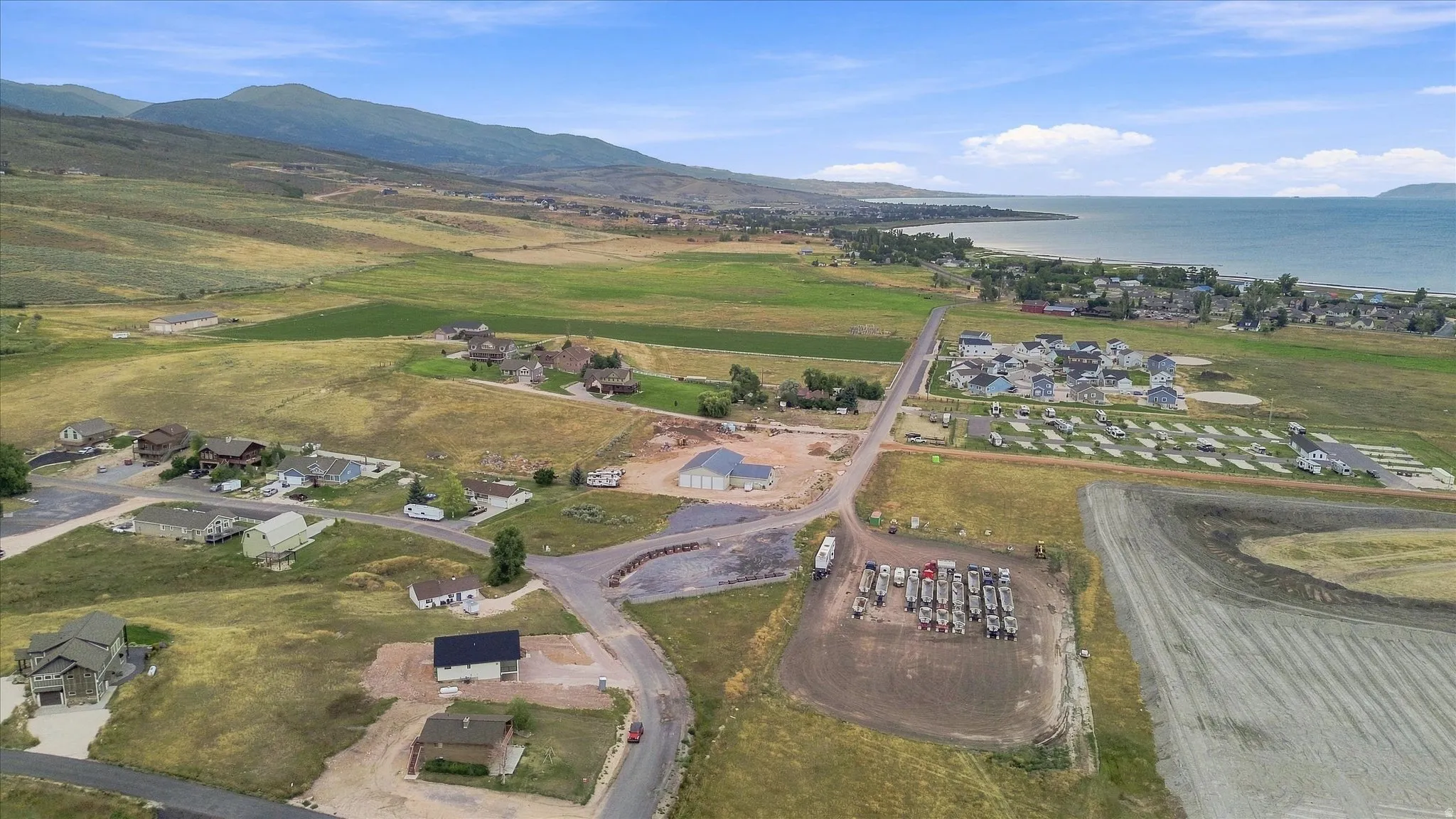 Mountain backdrop, expansive body of water, scattered residential structures, and established roadways