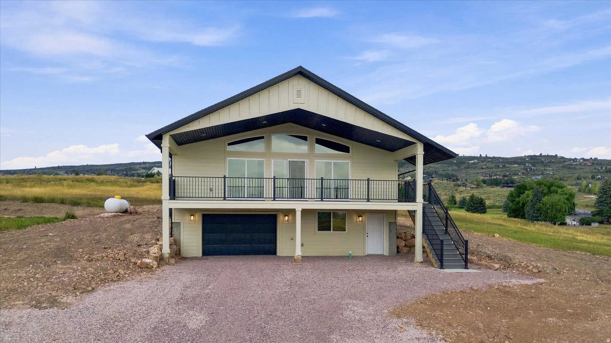 Two-story residence with a metal roof and a spacious balcony featuring black railings