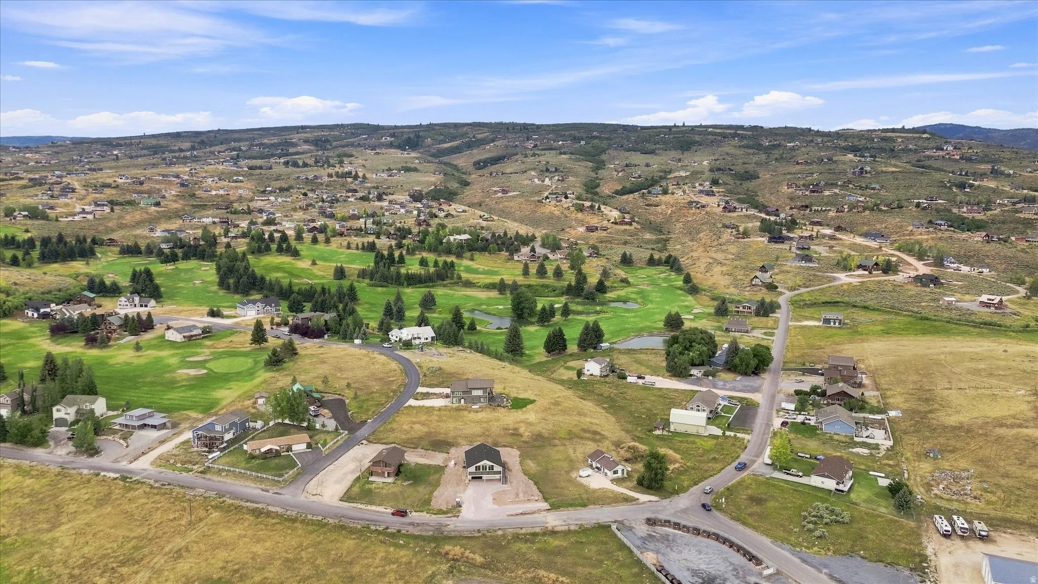 Expansive residential area featuring a golf course with multiple greens and water features, surrounded by mature trees and natural landscaping