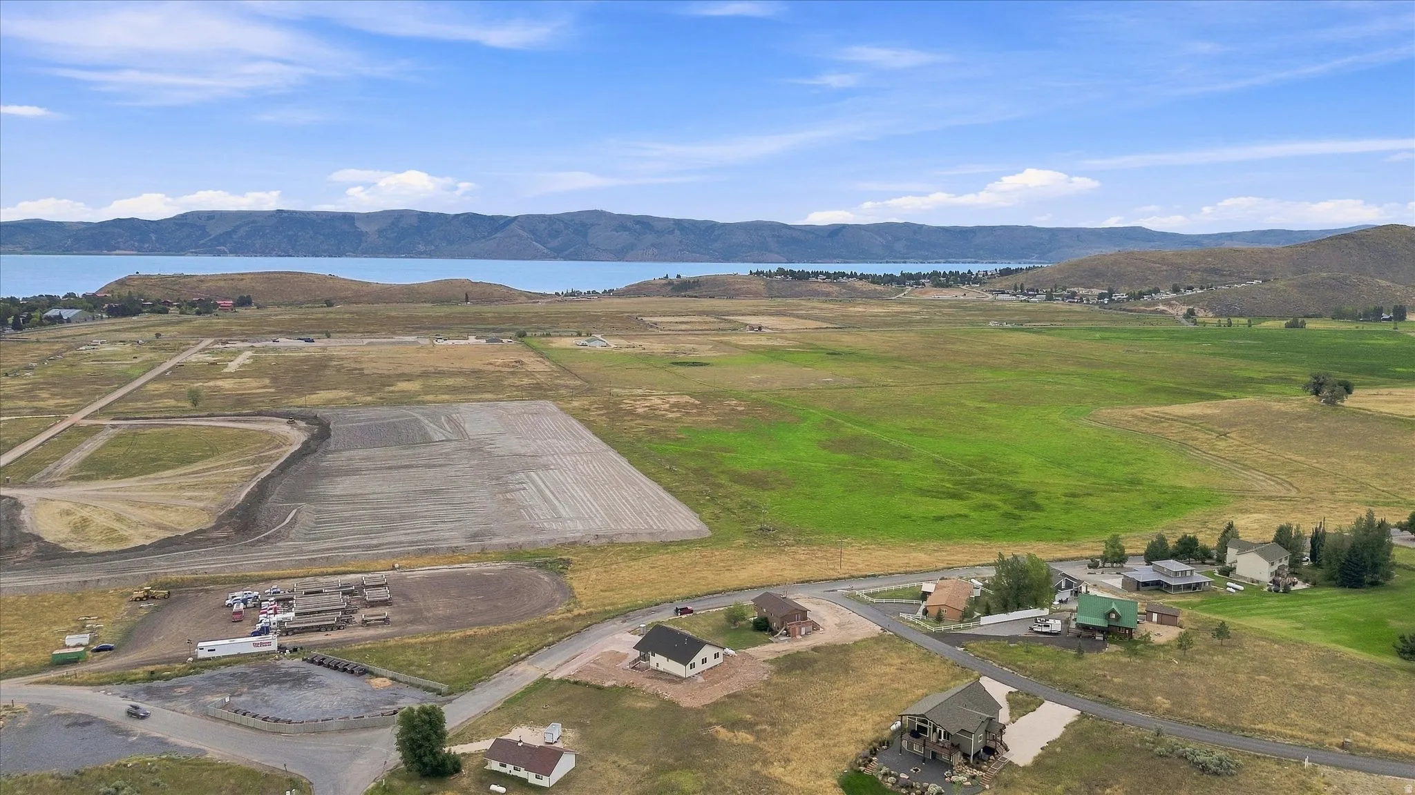 Expansive landscape featuring large parcels of land, a distant body of water, and surrounding hills