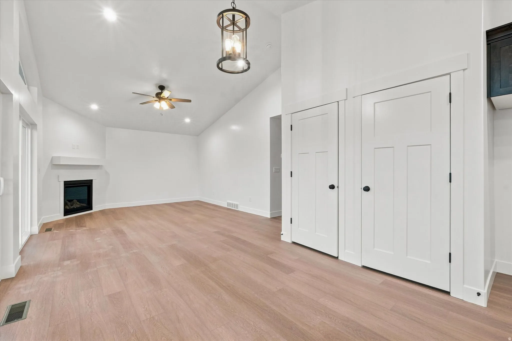 Vaulted ceiling with recessed lighting, wood-finish flooring, and a built-in fireplace