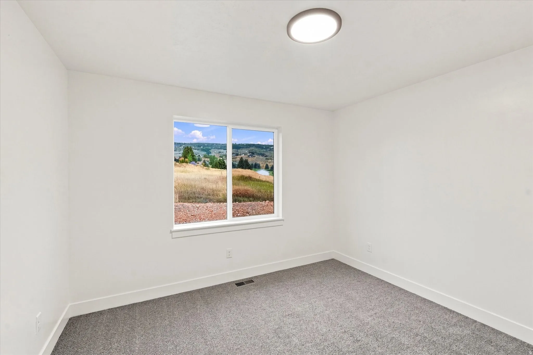 Window framing expansive hillside and distant water scenery