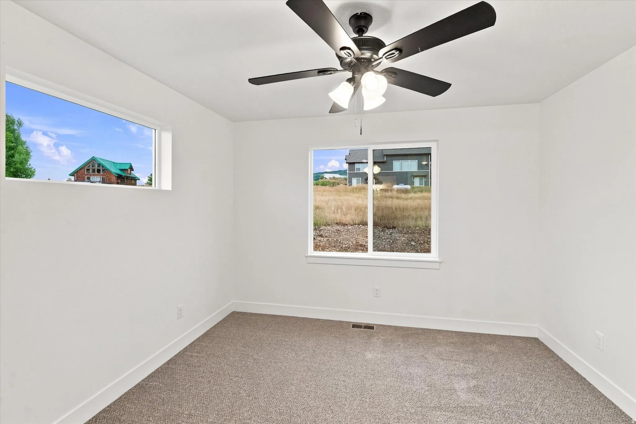 Neutral wall paint, plush carpet flooring, ceiling fan with integrated lighting, and multiple windows