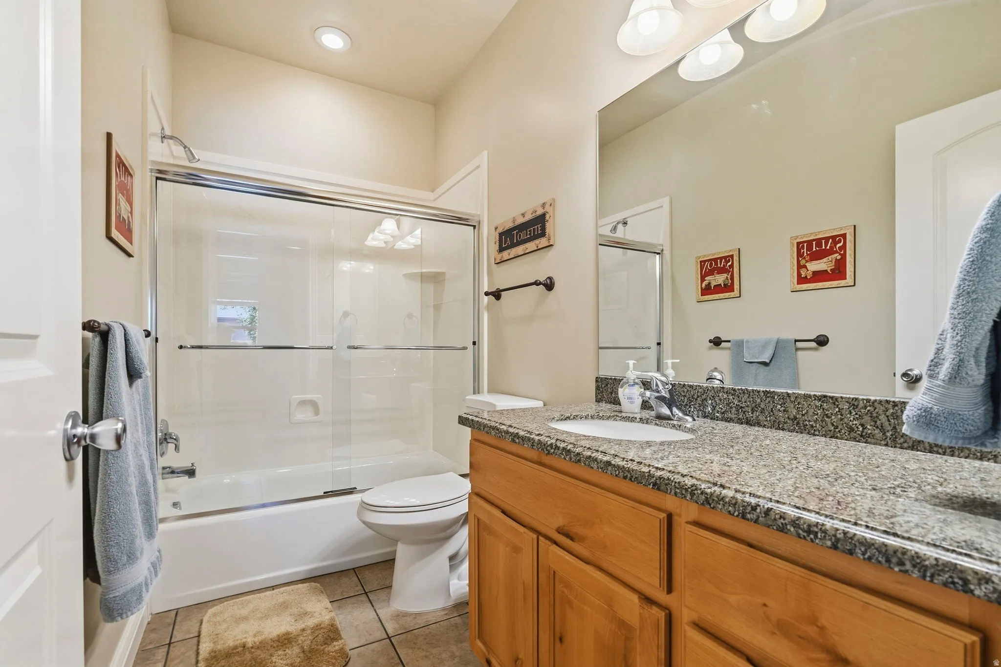Bathtub with sliding glass enclosure, recessed lighting, double vanity light fixture, integrated sink, and wood-finish cabinetry