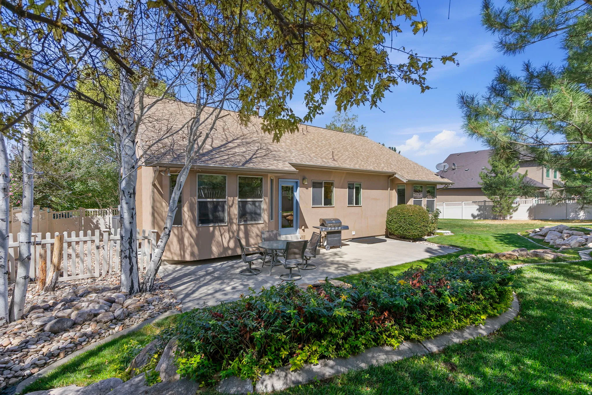Expansive backyard featuring a manicured lawn, established plantings, a paved patio, and mature trees