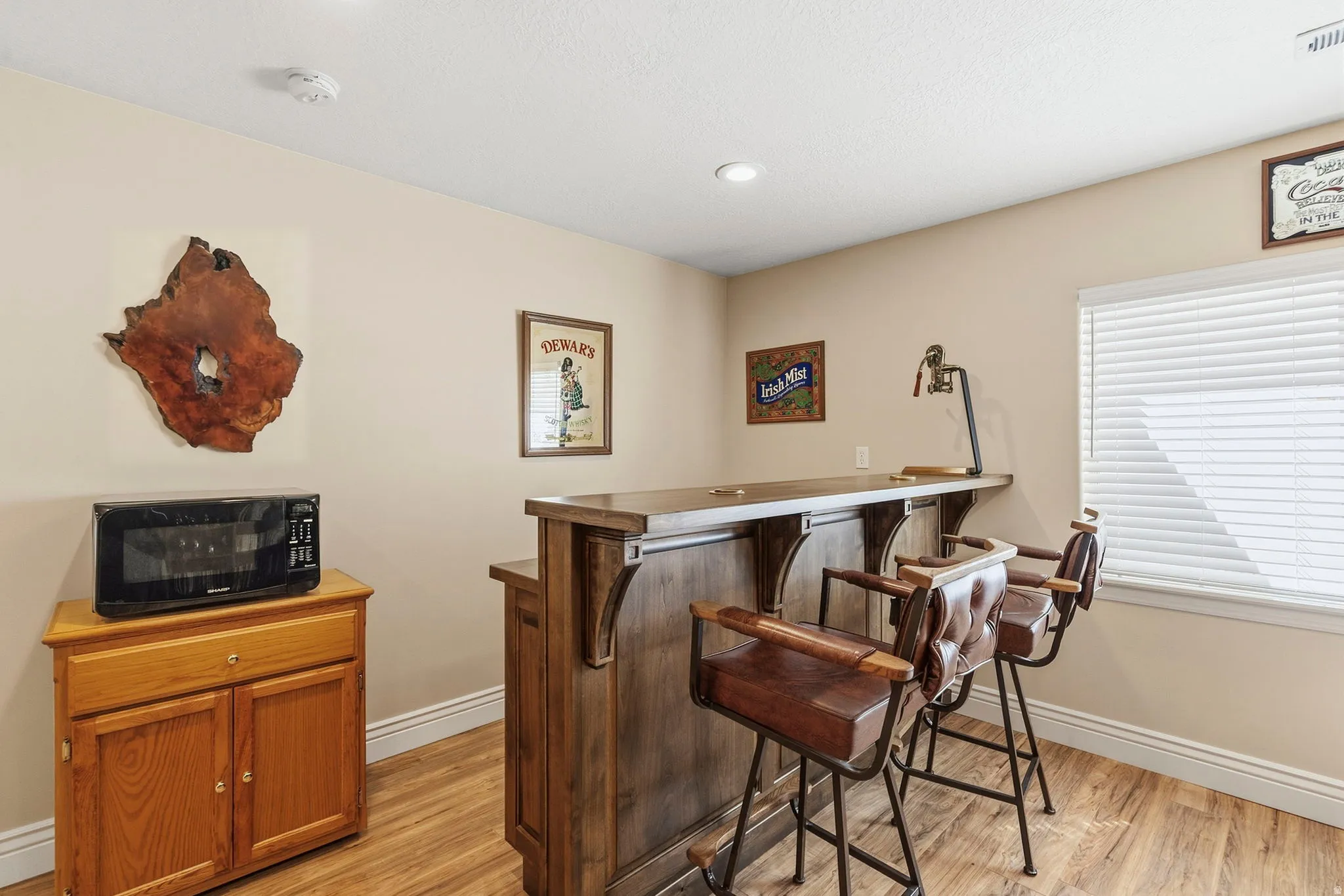 Wood-finish flooring, recessed lighting, and a built-in bar with a wooden countertop