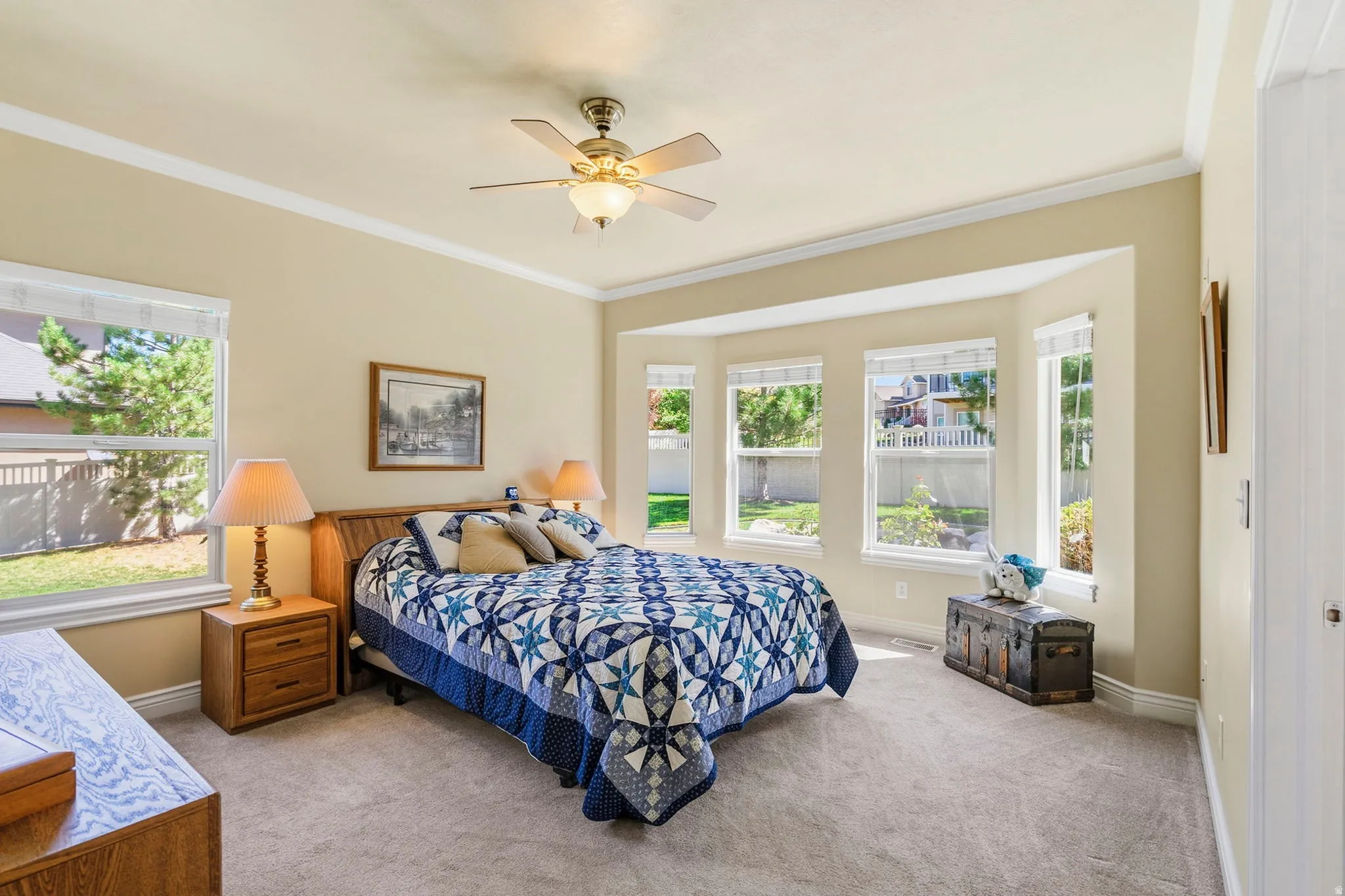 Carpeted room featuring a bay window, crown molding, and a ceiling fan with light fixture