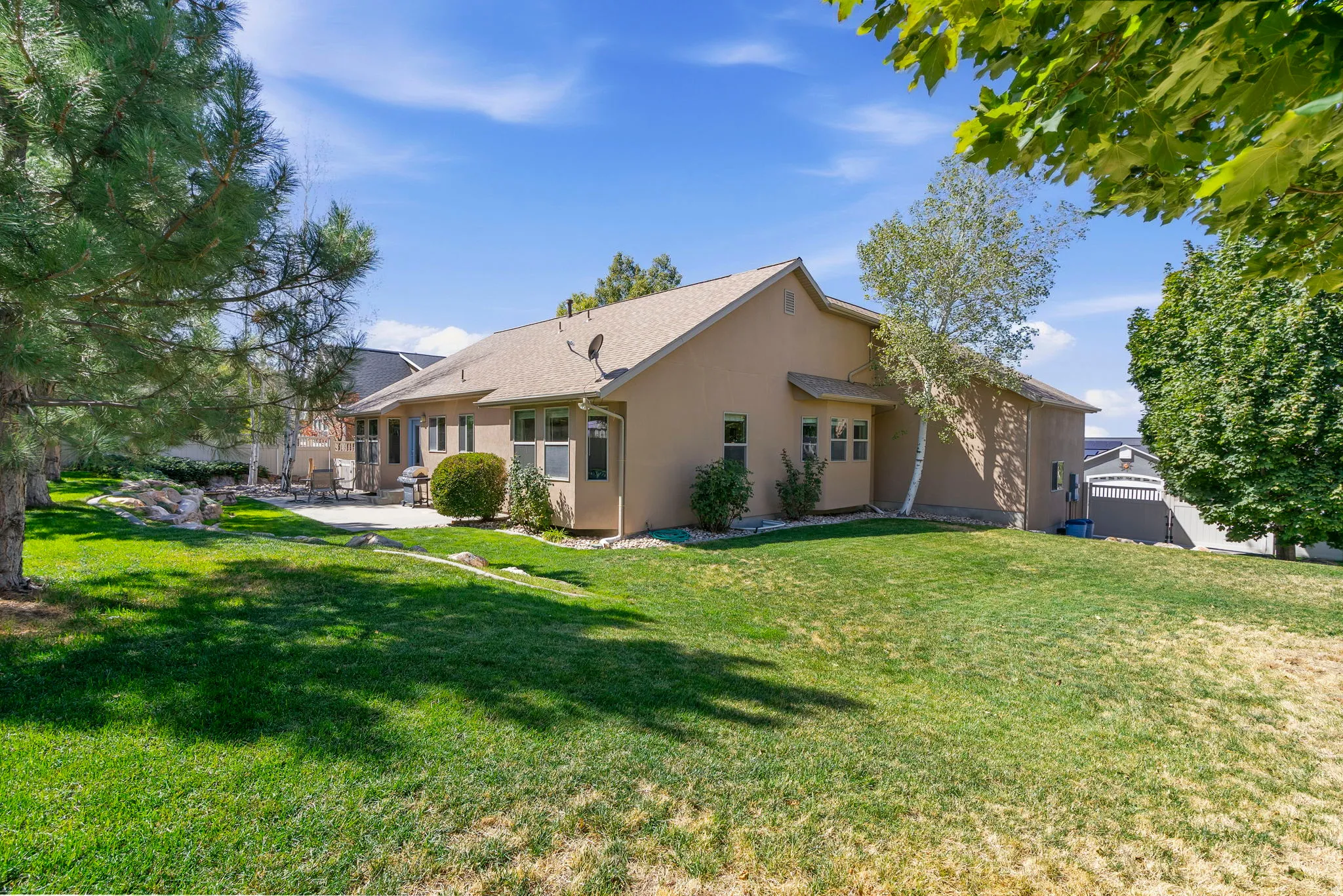 Expansive lawn with mature trees and a paved patio area