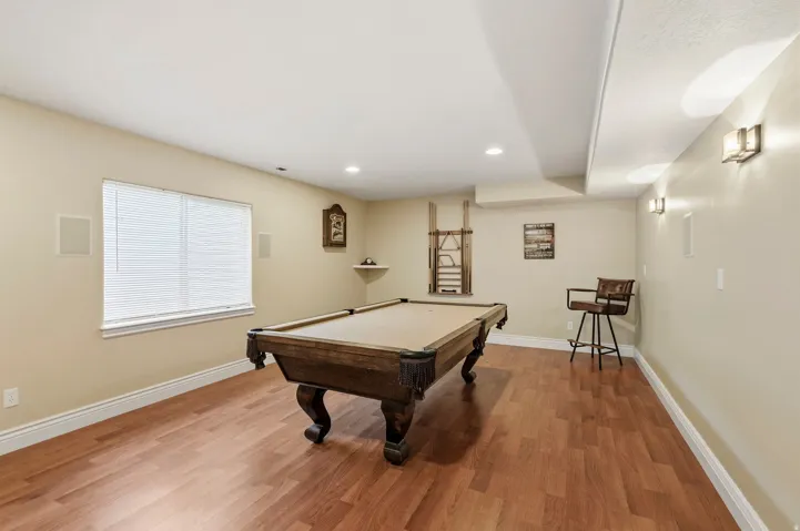 Recessed lighting, wood-finish flooring, and multiple wall sconces provide illumination