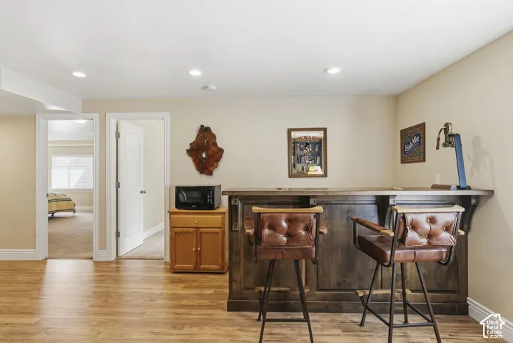 Wood-finish flooring throughout, featuring a built-in wood-paneled bar with integrated shelving, and recessed lighting