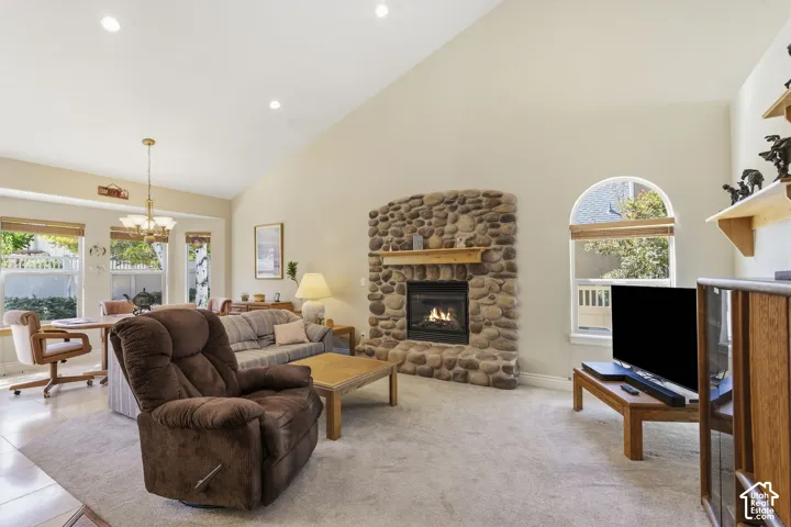Vaulted ceilings, recessed lighting, stone-clad fireplace with wood mantel, multiple windows, and arched window accent