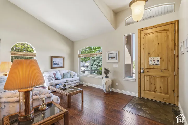 Vaulted ceiling with an arched transom window, natural wood-finish door, tile entry, and wood-finish flooring