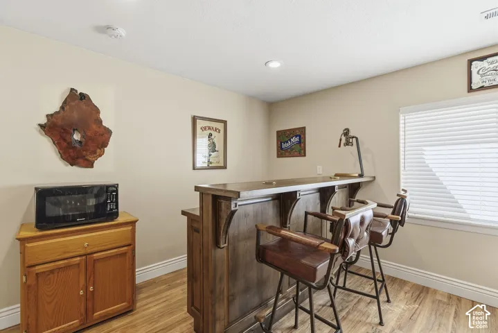 Wood-finish flooring, recessed lighting, and a built-in bar with a wooden countertop
