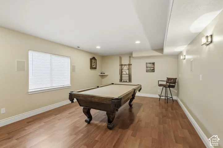 Recessed lighting, wood-finish flooring, and multiple wall sconces provide illumination