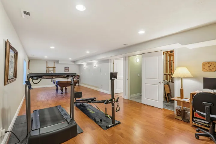 Spacious finished area featuring wood-finish flooring, recessed lighting, and white trim