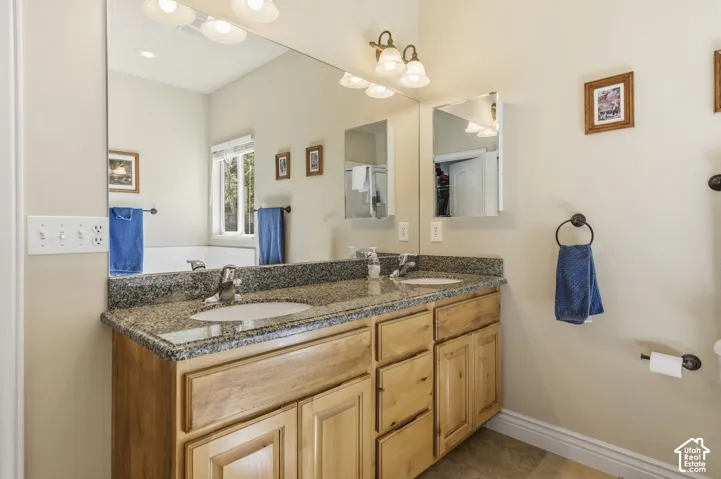 Dual vanity with light wood cabinetry, granite countertop, and undermount sinks