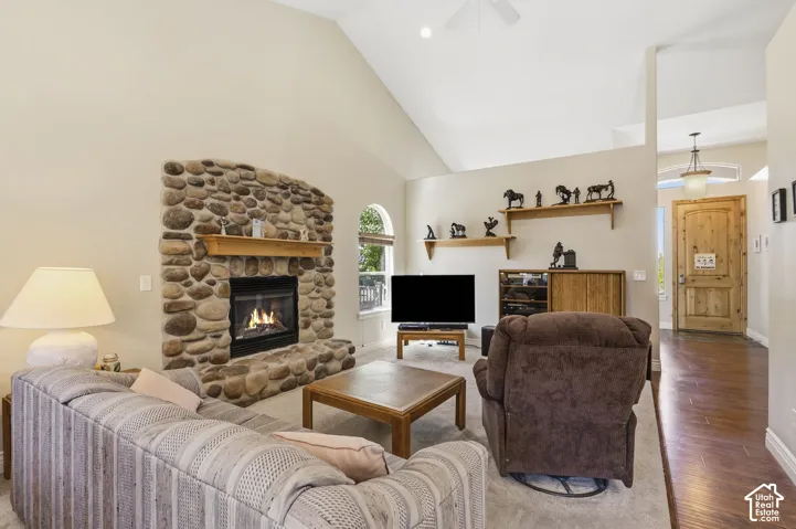 Vaulted ceiling, stone-clad fireplace with mantel, arched window, wood-finish flooring, paneled entry door