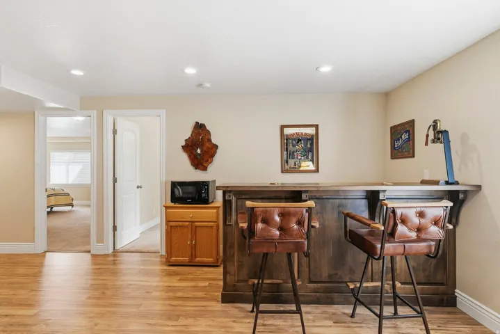 Wood-finish flooring throughout, featuring a built-in wood-paneled bar with integrated shelving, and recessed lighting