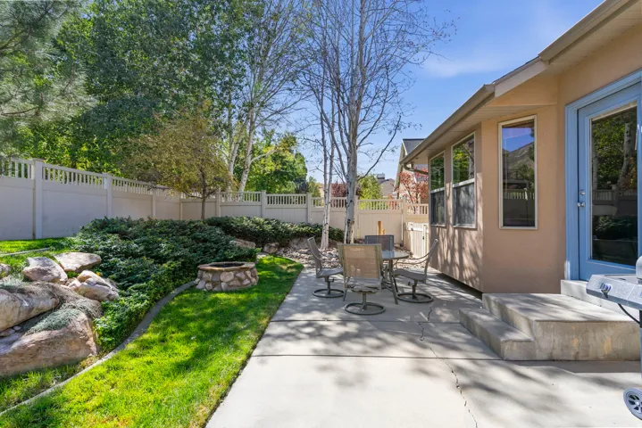 Concrete patio with multi-level steps, stone fire pit, and privacy fencing