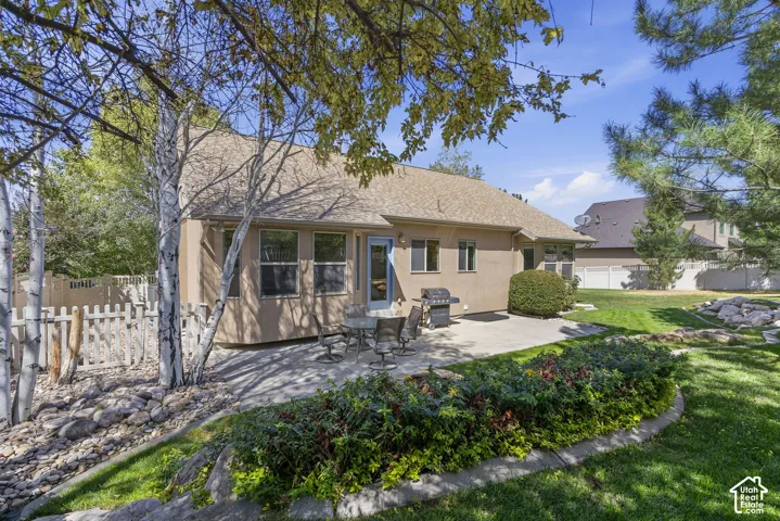 Expansive backyard featuring a manicured lawn, established plantings, a paved patio, and mature trees