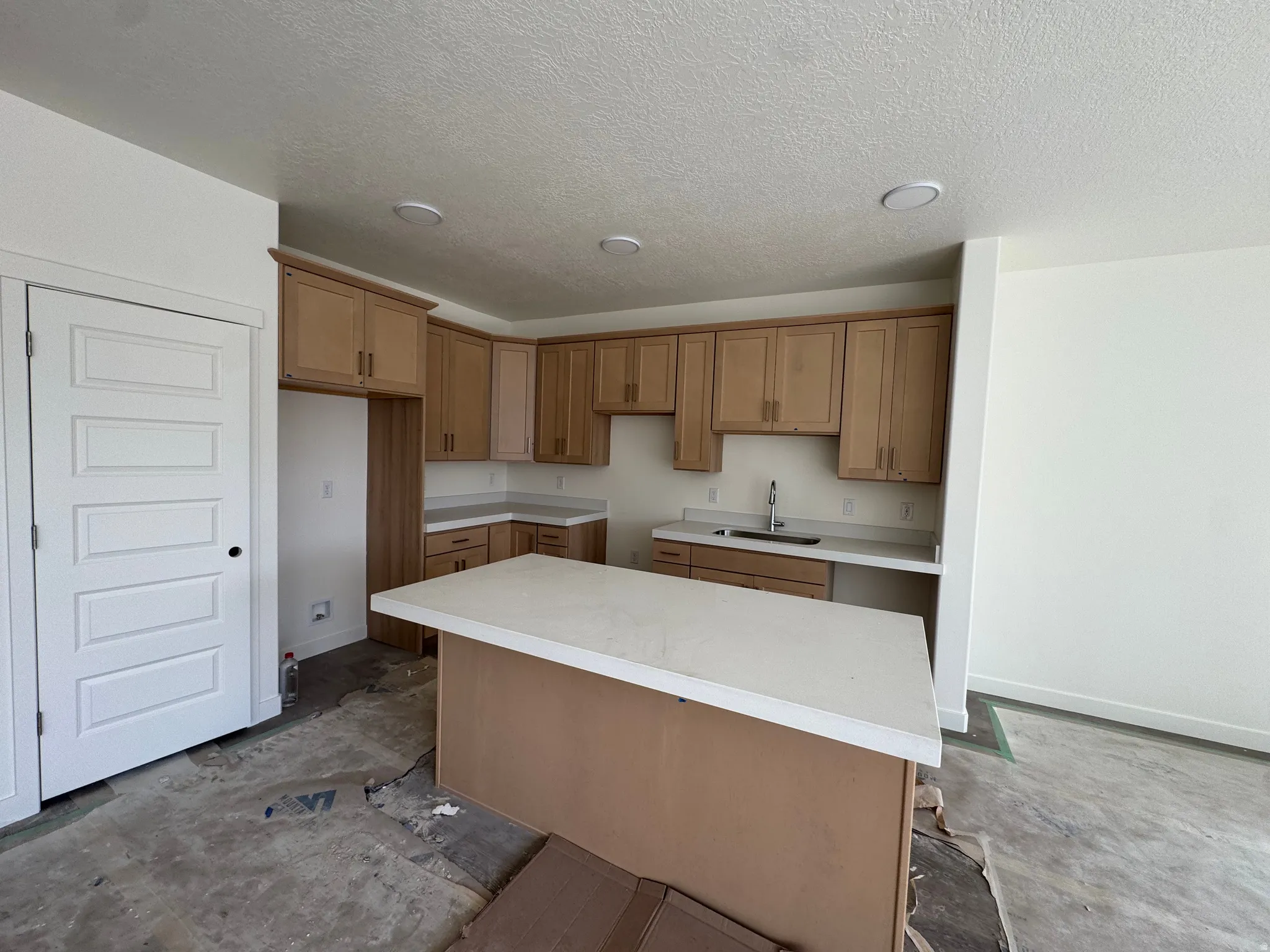Kitchen featuring light wood-finish cabinetry, light-toned countertops, and an integrated sink with a chrome faucet