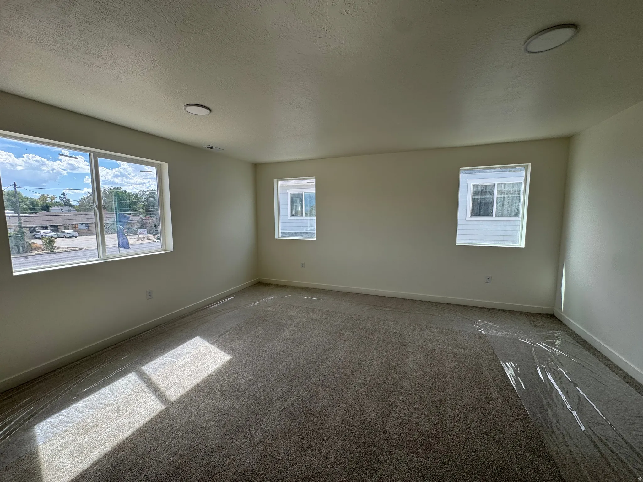 Carpeted room with multiple windows, recessed lighting, and neutral wall finishes