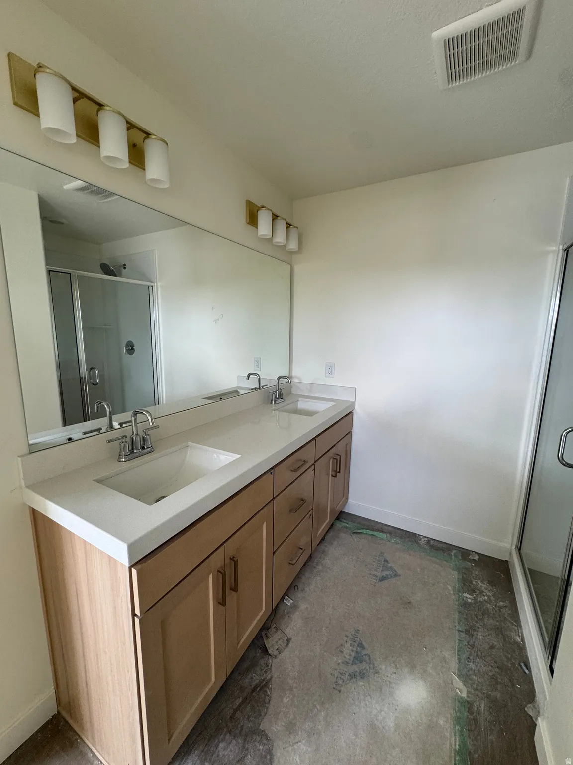 Dual vanity with light wood-finish cabinetry, integrated sinks, and polished chrome fixtures