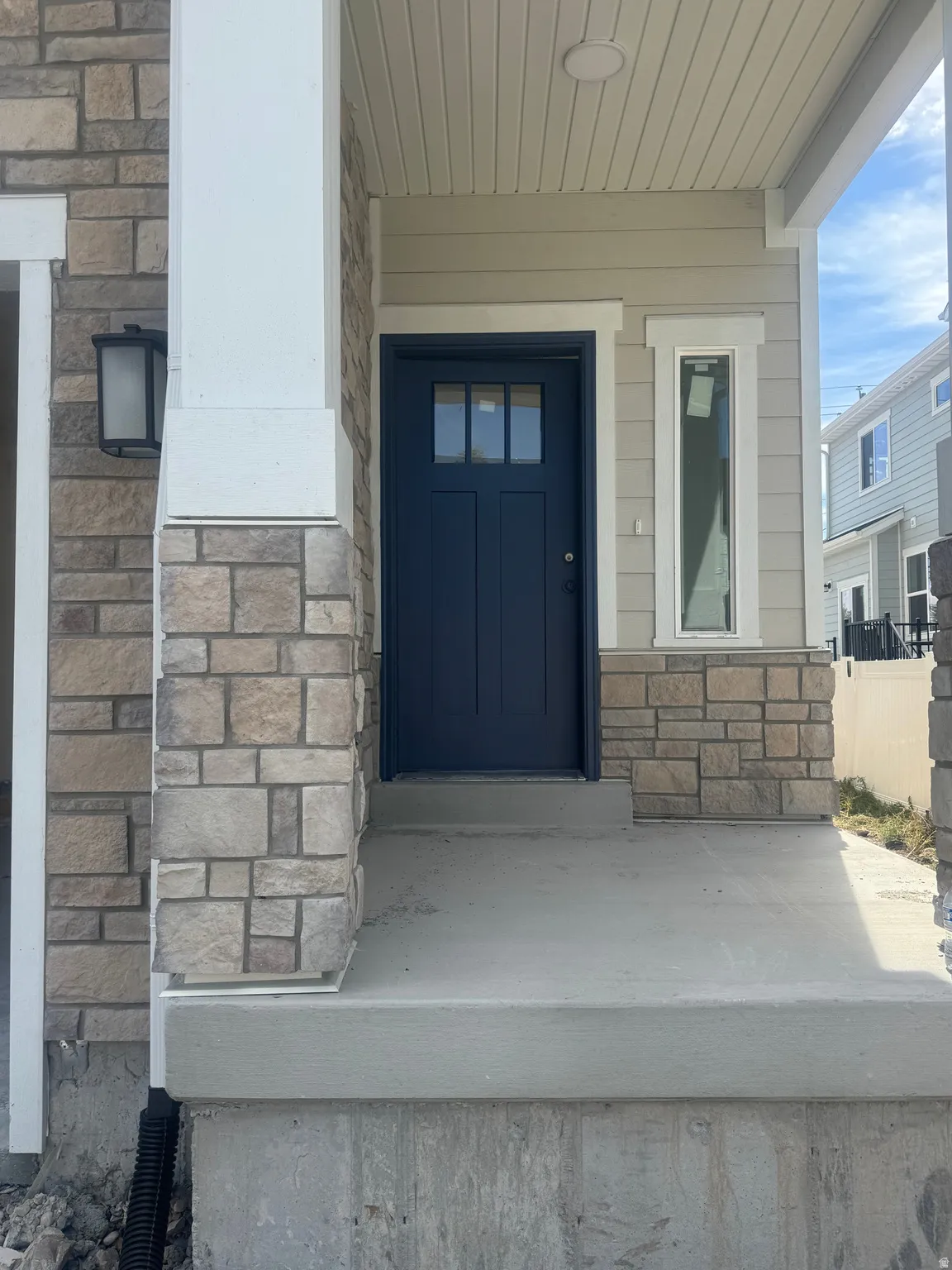 Stone veneer siding, covered entry, and a contrasting blue front door with windowpanes