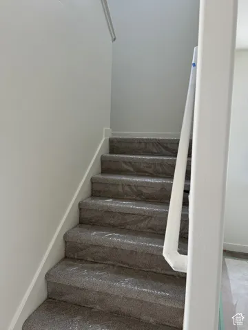 Staircase with carpeted treads and a white painted handrail