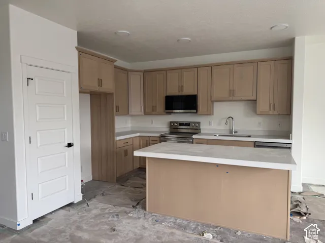 Kitchen featuring light wood-finish cabinetry, stainless steel appliances, a center island with a light countertop, and recessed lighting