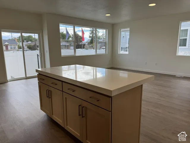 Kitchen island featuring a stone countertop, wood-finish cabinetry, recessed lighting, and large windows