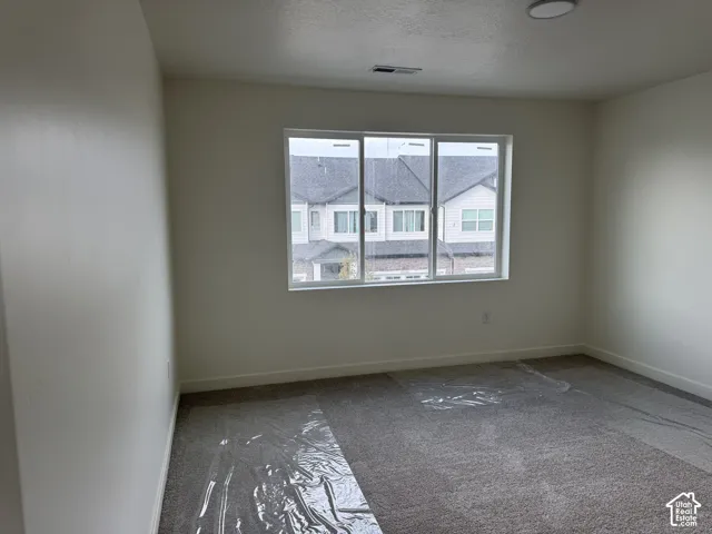 Neutral wall paint, gray carpeting, and a window with white trim
