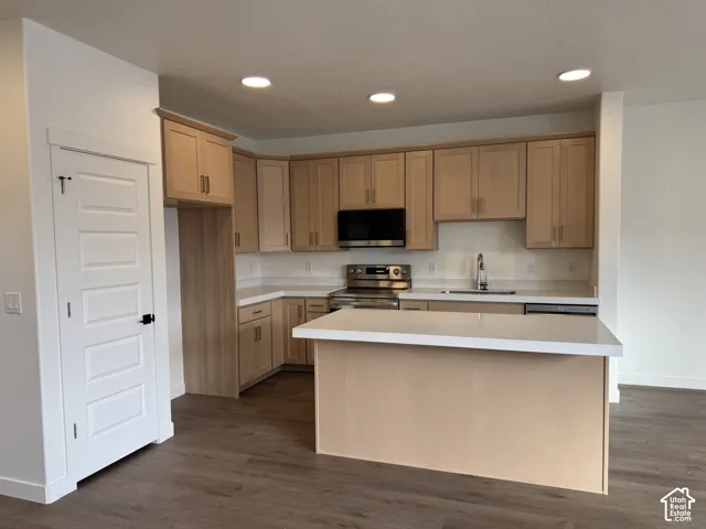 Kitchen featuring flat-panel wood-finish cabinetry, white countertops, stainless steel appliances, a center island, and wood-finish flooring