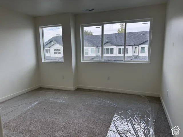 Neutral wall paint, plush carpeting, multiple windows providing natural illumination, and white trim