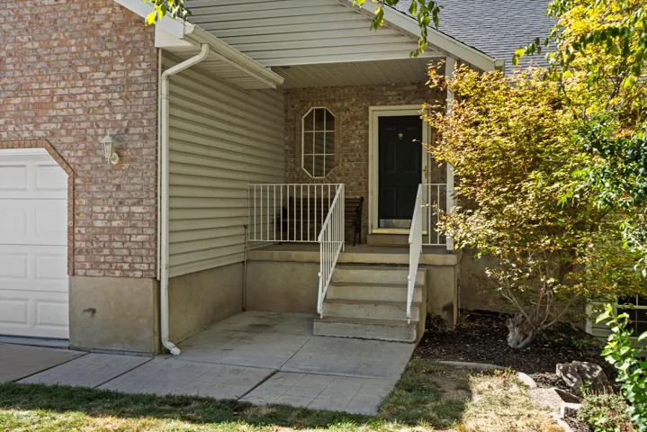 Brick and siding exterior with a covered porch, concrete steps, and white railing
