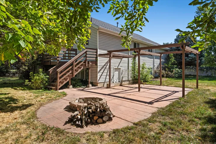 Backyard featuring a paver patio with a pergola, a stone fire pit, and a wooden deck with stairs