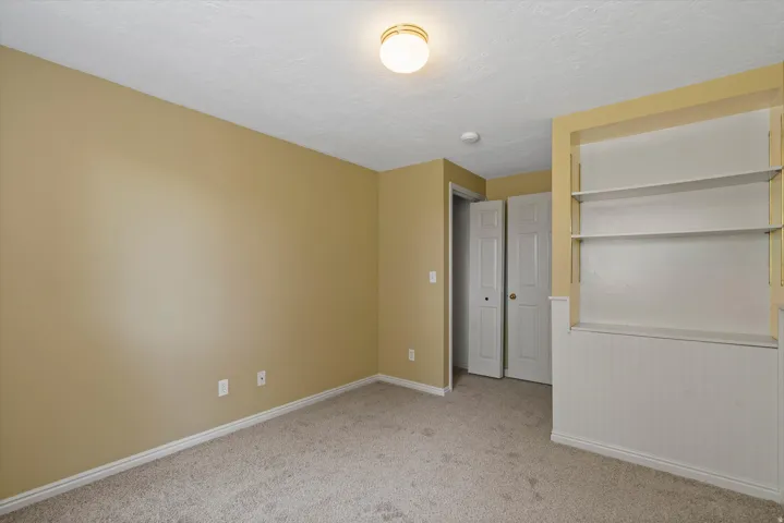 Wall-to-wall carpeting, built-in shelving, bifold closet doors, and flush mount lighting
