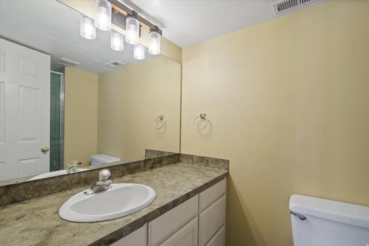 Bathroom featuring a single vanity with an integrated sink, patterned countertop, and light-toned cabinetry