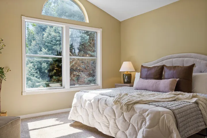 Vaulted ceiling with an arched transom window, large double-hung window, and neutral-toned wall paint