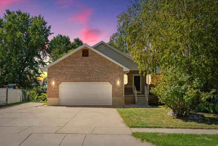 Brick exterior with siding accents, two-car garage, concrete driveway, front porch with railings, and mature landscaping